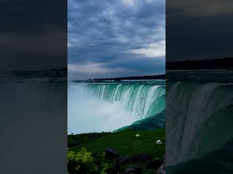 Turquoise water flowing over Niagara Falls beneath a cloudy sky