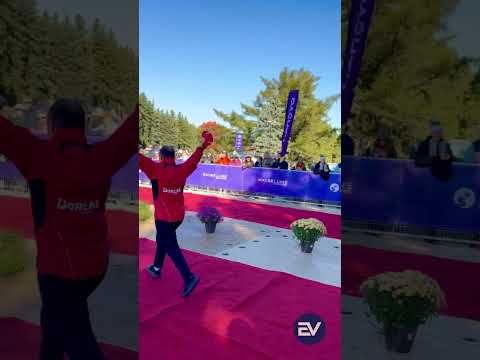 A runner raising both arms in celebration at the Montréal marathon finish line